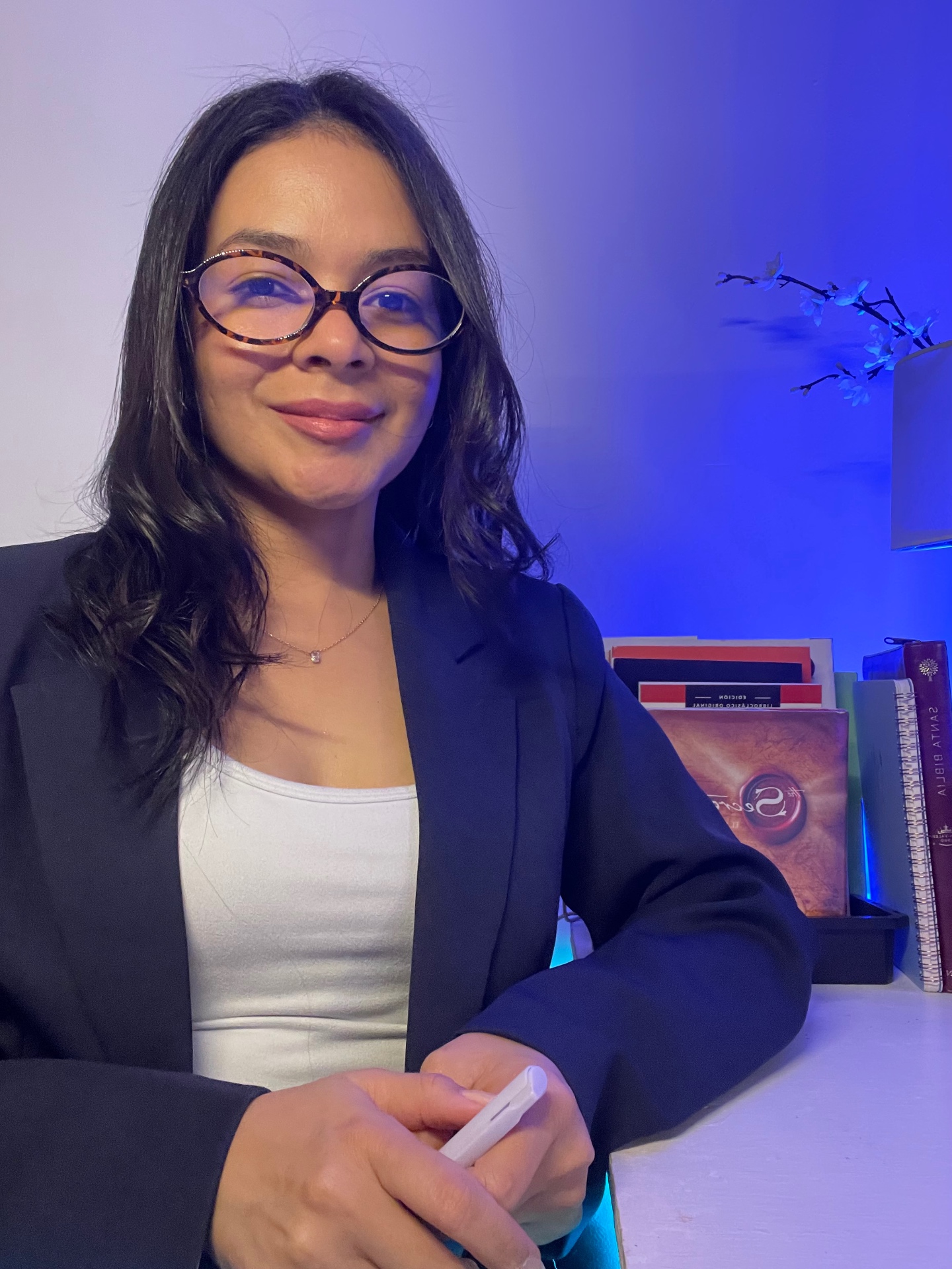 Yeimi Álvarez sonriendo en su escritorio junto a sus libros y su Biblia